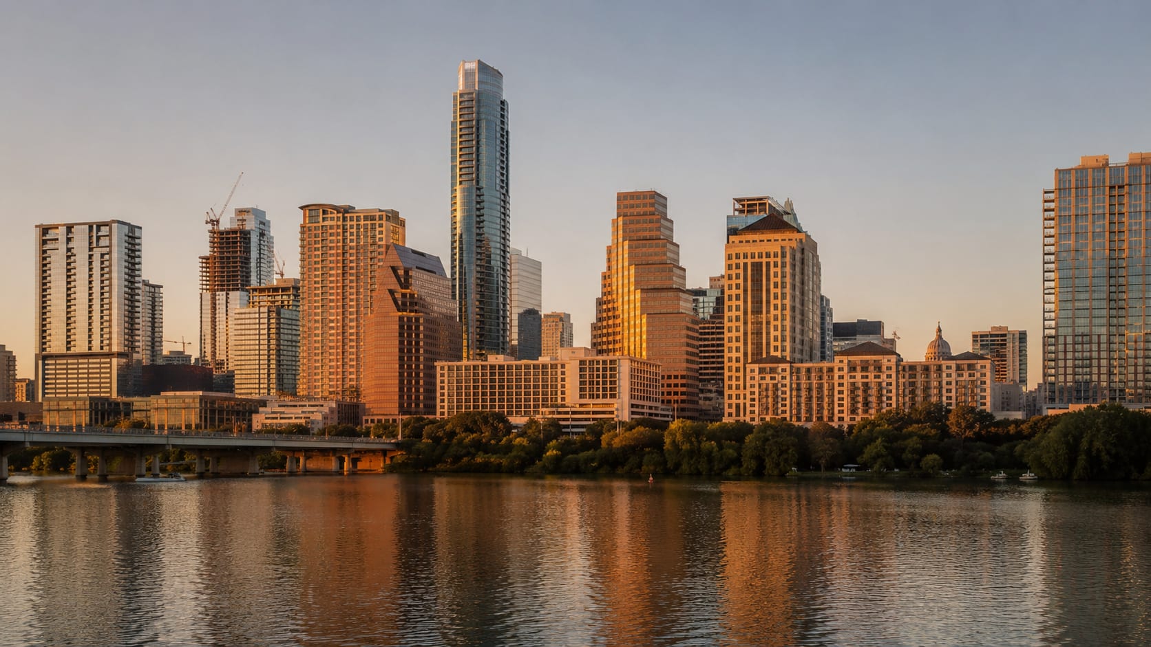 Downtown Austin skyline rising above Lady Bird Lake at golden hour, with the Pennybacker Bridge and Hill Country in the distance